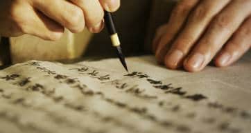 Person writing Japanese calligraphy in traditional style