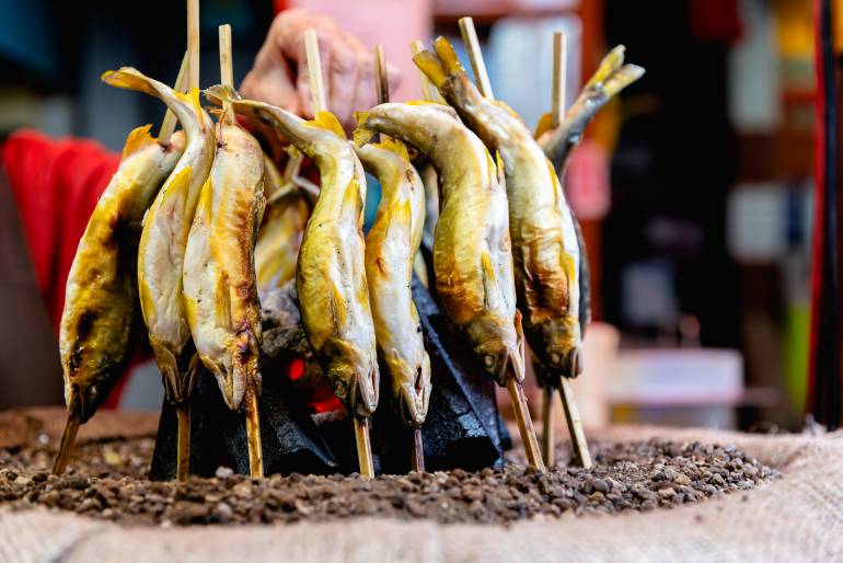 Ayu fish being grilled with salt, Japanese ayu sweetfish cooking around hot charcoals.