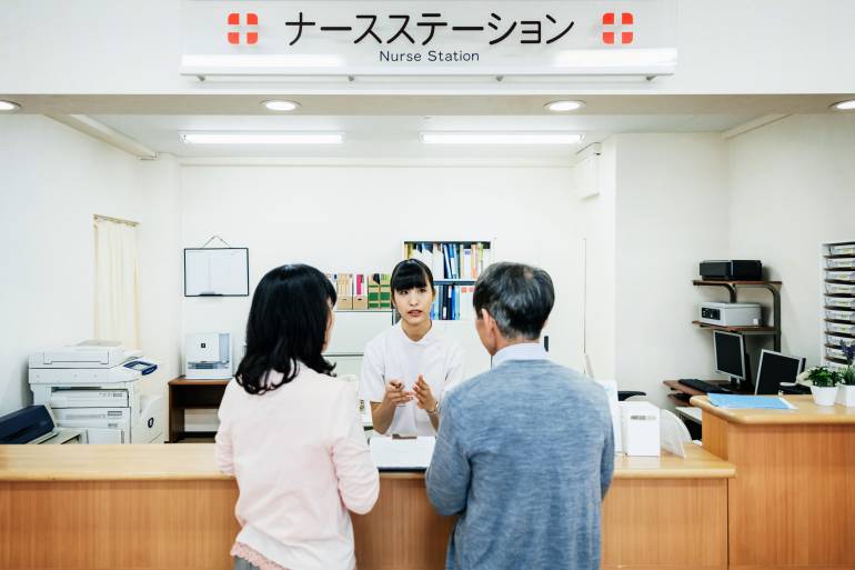 A nurse is talking to a couple and going through details of their stay at a Japanese Hospital.